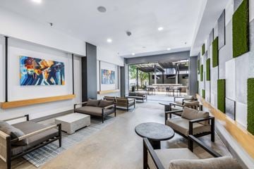 Fort Worth apartment for rent - A modern living room with a large painting on the wall and a green plant on the side.