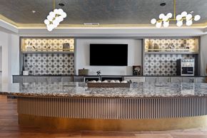 Nashville apartment for rent - A modern bar with a dark counter top and a television mounted on the wall.