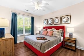 Morrisville apartment for rent - A bedroom with a bed, nightstand, and a window with blue curtains.