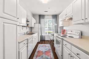Raleigh apartment for rent - A kitchen with white cabinets and a red rug on the floor.