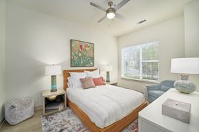 Richmond apartment for rent - A bedroom with a large bed, a ceiling fan, and a painting on the wall.