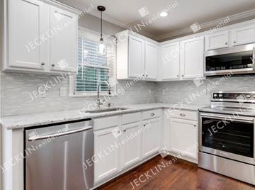 Henrico house for rent - A modern kitchen with white cabinets and stainless steel appliances.