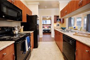 Cary apartment for rent - a kitchen with wood cabinets and black appliances and counter tops