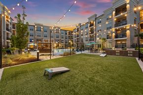 Buford apartment for rent - A sunset view of a grassy area with a bench and apartment buildings in the background.