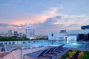 Fort Worth apartment for rent - A rooftop pool area with lounge chairs and a city skyline in the background.