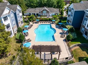 Wake Forest apartment for rent - A large swimming pool surrounded by a wooden deck and umbrellas.