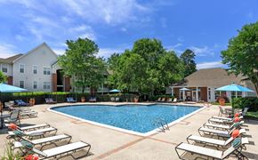 Midlothian apartment for rent - A pool surrounded by sun loungers and umbrellas with a building in the background.