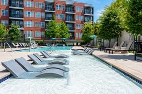 Nashville apartment for rent - A large swimming pool with lounge chairs and a building in the background.