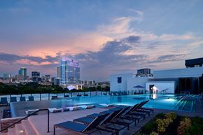 Fort Worth apartment for rent - A rooftop pool area with lounge chairs and a city skyline at dusk.