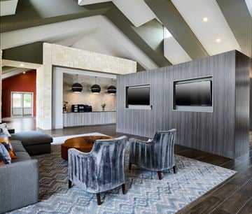 Mckinney apartment for rent - A modern living room with grey chairs and a stone wall.