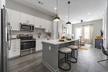 White shaker-style cabinetry with gray kitchen island with black fixtures