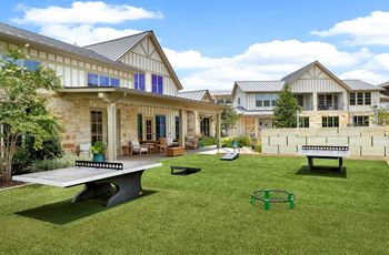 Outdoor poolside game area with corn hole and ping pong tables