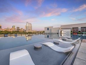 Fort Worth apartment for rent - a rooftop pool with lounge chairs and a view of the city