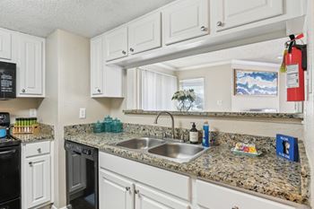 A kitchen with granite countertops and white cabinets