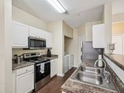 Raleigh apartment for rent - A kitchen with a black oven and white cabinets. at Cedar Springs Apartments, North Carolina, 27609