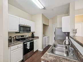 Raleigh apartment for rent - A kitchen with a black oven and white cabinets. at Cedar Springs Apartments, North Carolina, 27609