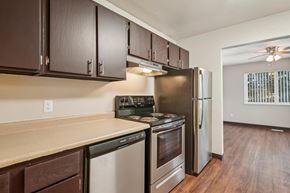 Colorado Springs apartment for rent - A kitchen with dark brown cabinets and stainless steel appliances.at Aspen Townhomes, Colorado Springs, CO