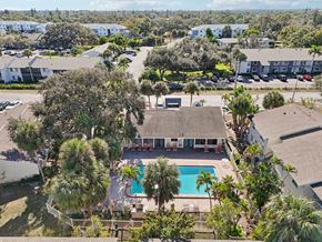 Bradenton apartment for rent - A swimming pool is surrounded by palm trees and a building.