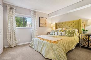 Broomfield apartment for rent - A bedroom with a large bed and a window with curtains. at Deer Crest Apartments, Broomfield, Colorado