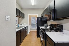 Dallas apartment for rent - A kitchen with black cabinets and white countertops at The Willows on Rosemeade, Dallas, TX 75287