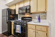 Orlando apartment for rent - A kitchen with a black refrigerator and stove top oven. at University Park Apartments, Florida