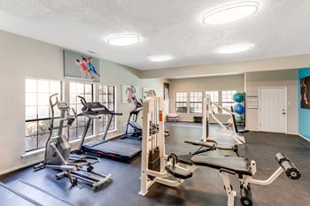 A gym with a variety of exercise equipment including treadmills, stationary bikes, and weight machines.