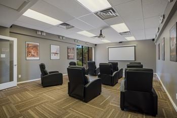 Screening room filled with black chairs and a white screen  
