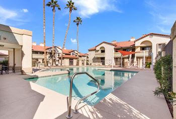 A pool surrounded by palm trees and buildings.