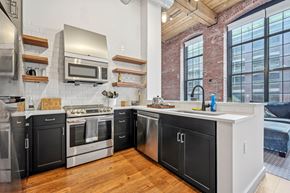 Lawrence apartment for rent - a kitchen with black and white cabinets and a large window at Riverwalk Apartments, Lawrence, MA