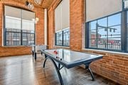 Lawrence apartment for rent - two ping pong tables in an empty game room with brick walls and large windows at Riverwalk Apartments, Lawrence, MA