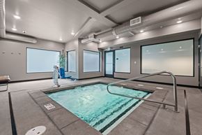 University Place apartment for rent - A person is standing by the pool in a room with large windows.