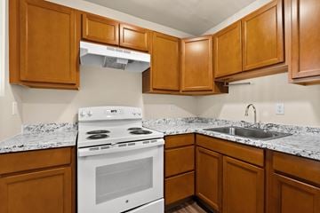 Olympia apartment for rent - a kitchen with a stove and sink and wooden cabinets