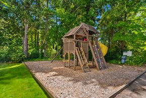 Bremerton apartment for rent - a swing set in a backyard with trees and a yellow slide