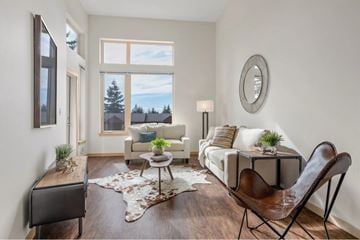 University Place apartment for rent - A living room with a white couch, a brown leather chair, and a rug with a cowhide pattern.