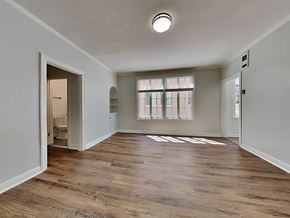 Oakland apartment for rent - an empty living room with a large window and a door to a bathroom