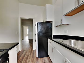 San Francisco apartment for rent - a kitchen with white cabinets and a black refrigerator
