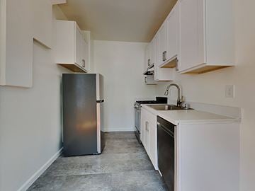 San Francisco apartment for rent - A kitchen with a black refrigerator and white cabinets.