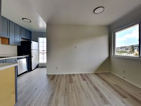 Oakland apartment for rent - an empty living room and kitchen with wood floors and a large window