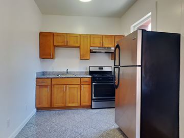 San Francisco apartment for rent - a kitchen with wooden cabinets and a black refrigerator