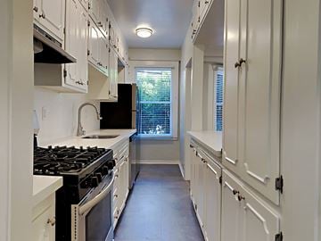 San Francisco apartment for rent - a kitchen with white cabinets and a stove and a window