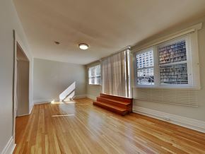 San Francisco apartment for rent - an empty living room with a staircase and a large window