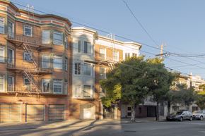 San Francisco apartment for rent - A row of apartment buildings with cars parked in front.