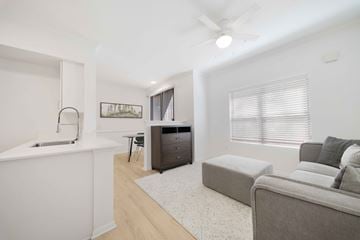 San Diego apartment for rent - A modern living room with a grey couch and a white kitchen area.