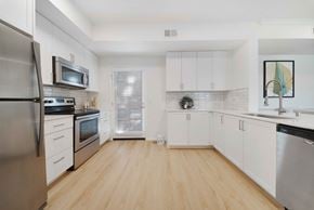San Diego apartment for rent - A kitchen with white cabinets and a wooden floor.