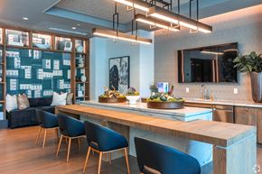 Dallas apartment for rent - A modern kitchen with a long wooden island and blue chairs.