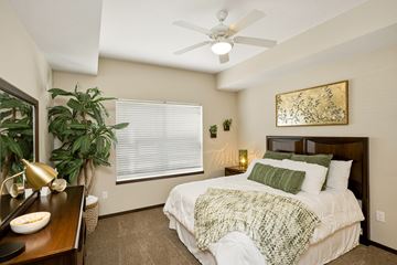 West Des Moines apartment for rent - A bedroom with a bed, a ceiling fan, and a painting on the wall.
