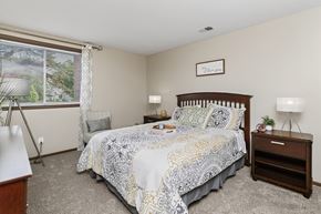 West Des Moines townhouse for rent - A bedroom with a bed, nightstand, and window.