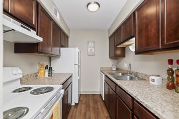 West Des Moines townhouse for rent - A kitchen with brown cabinets and a white stove top oven.