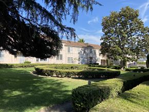 Los Angeles apartment for rent - a large building with a lawn and hedges in front of it