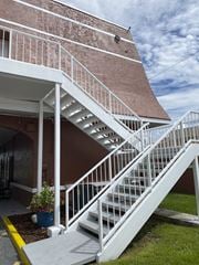 Orlando apartment for rent - a white staircase on the side of a building with a cloudy sky in the background at Colonial Drive Apartments, Orlando, FL 32808